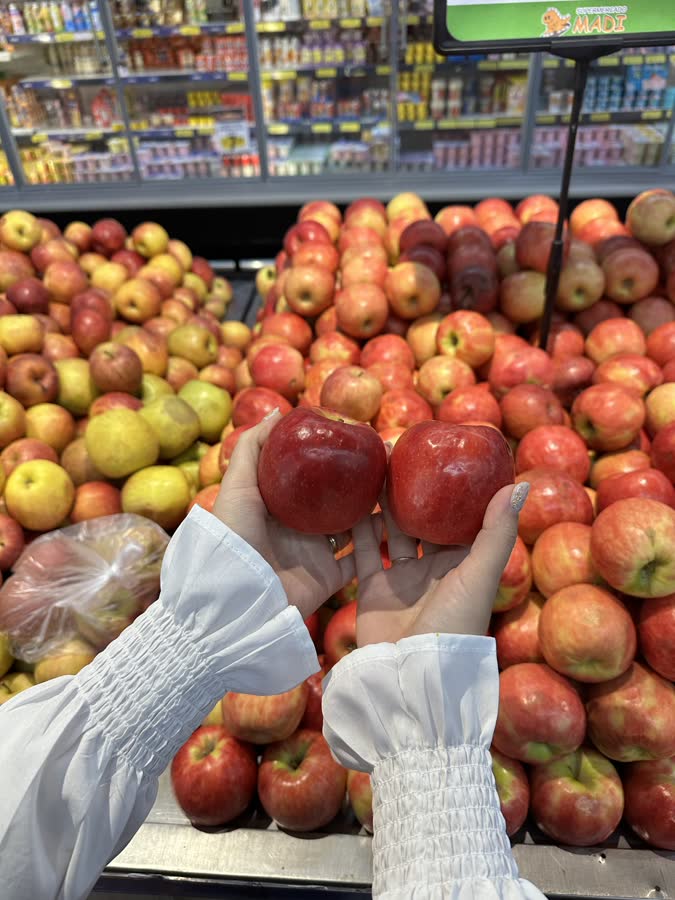 Maçãs vermelhas no hortifrúti, com uma sendo escolhida
